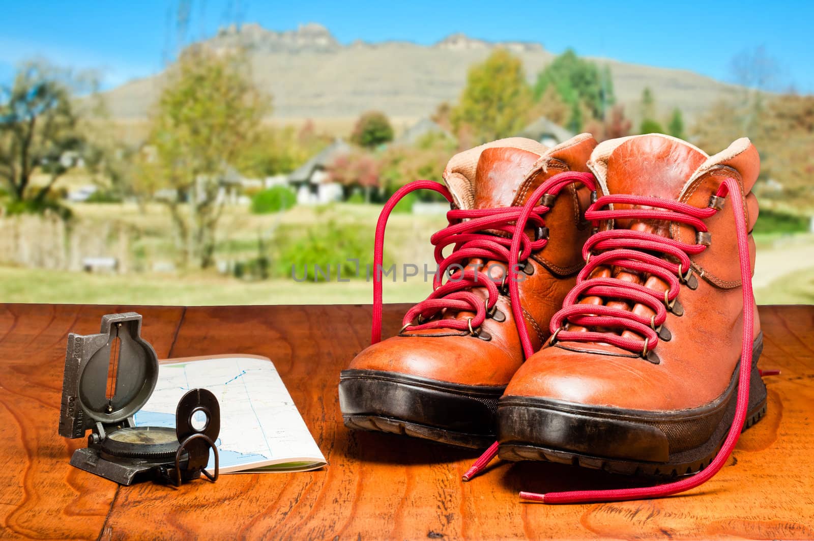 Hiking boots , map and compass with mountain in the background