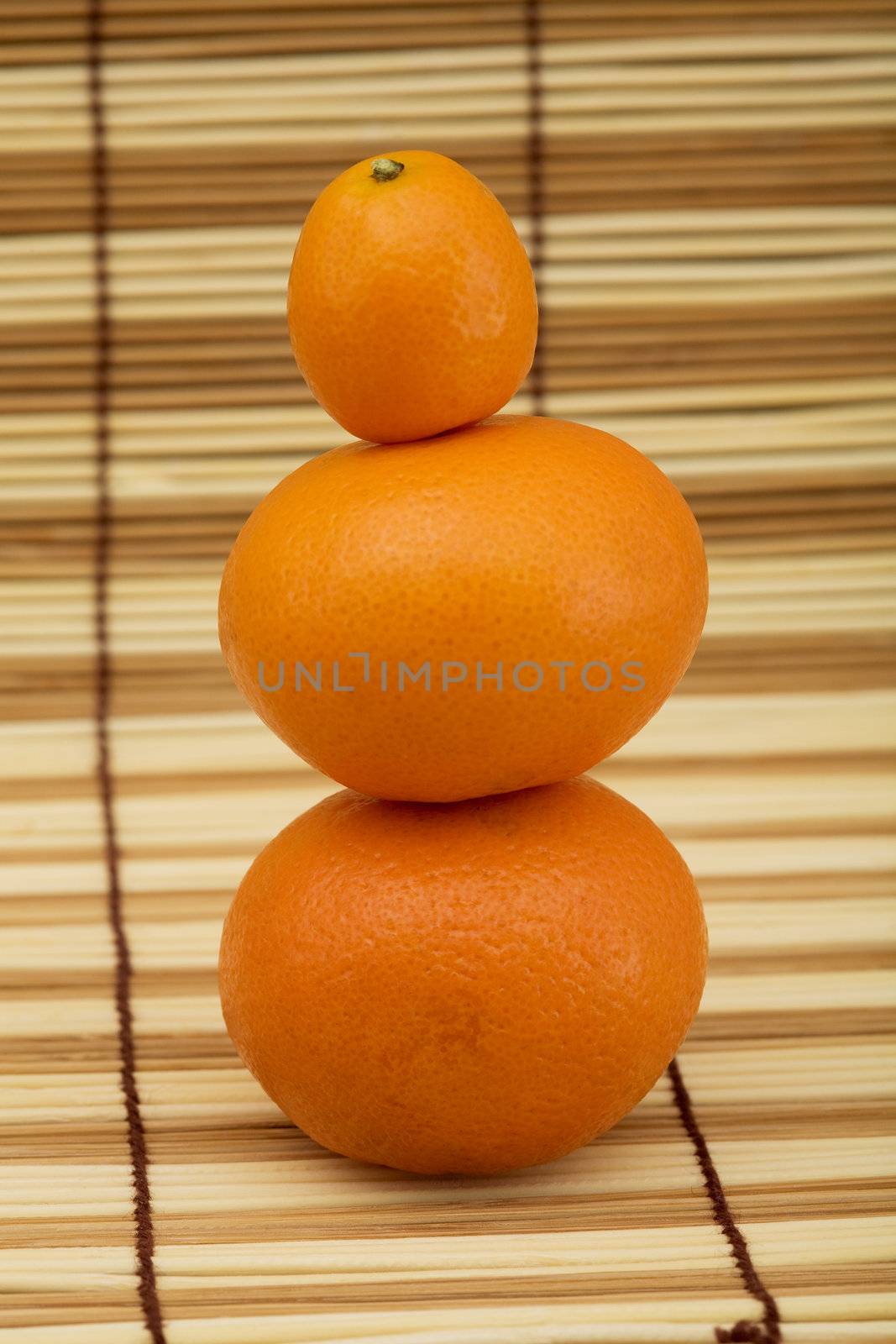 Two mandarin and kumquat on the wooden mat