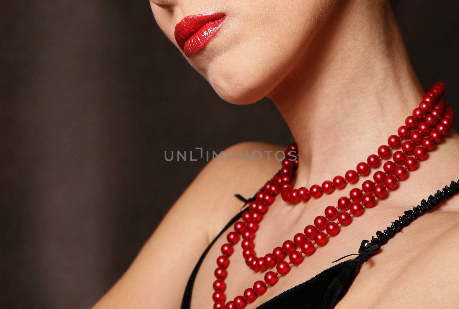 Beautiful woman wearing red pearls beads isolated on grey