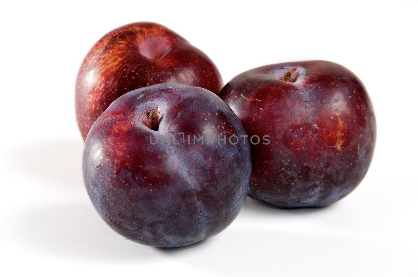 Three red plums on a white background.