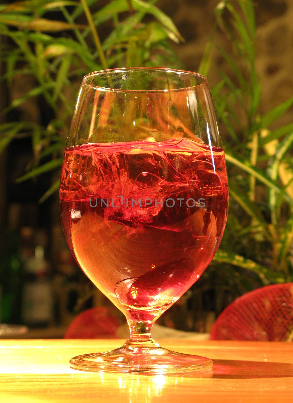 A red cocktail drink with ice.