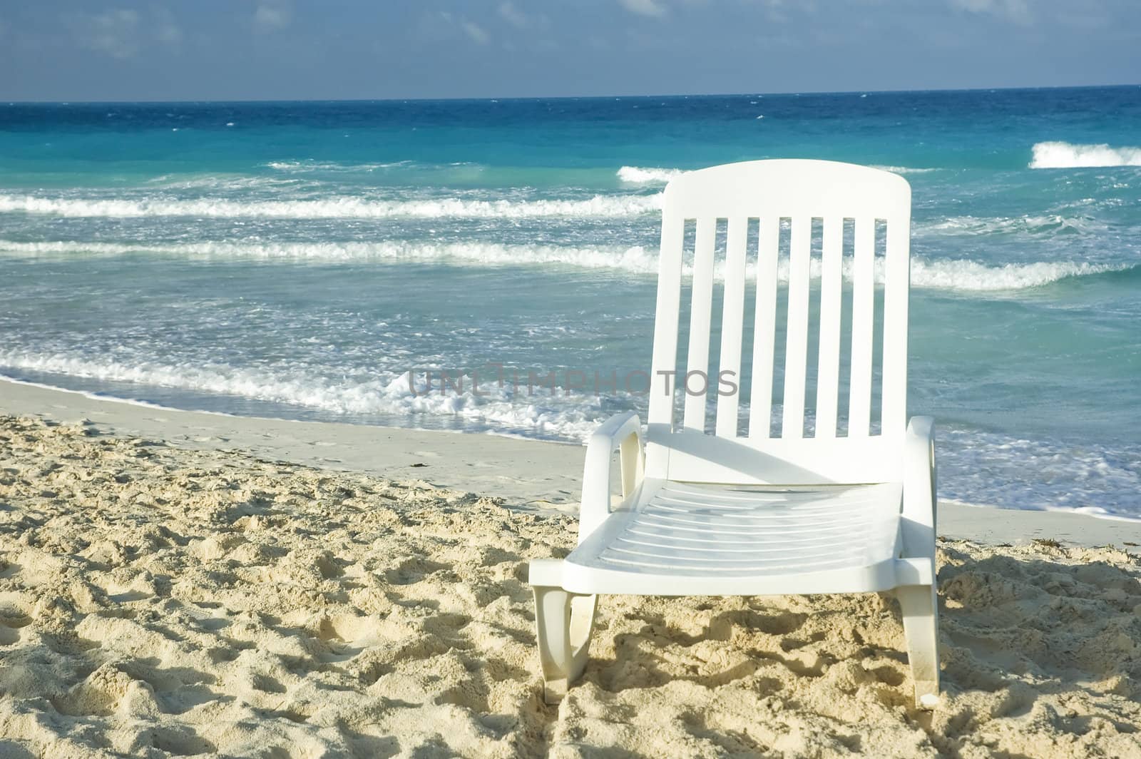 white plastic long chair on a sandy beach