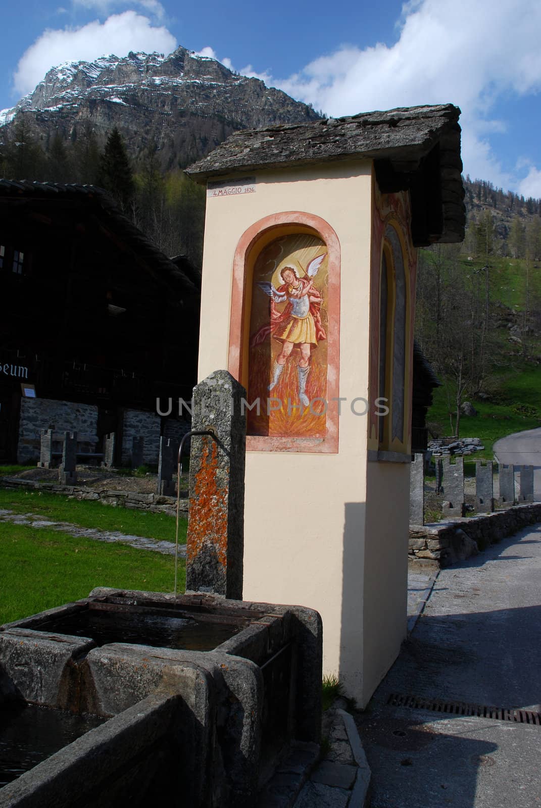 Water source place  in Bosco Gurin village decorated with the 19th century fresco, the village museum is at the background