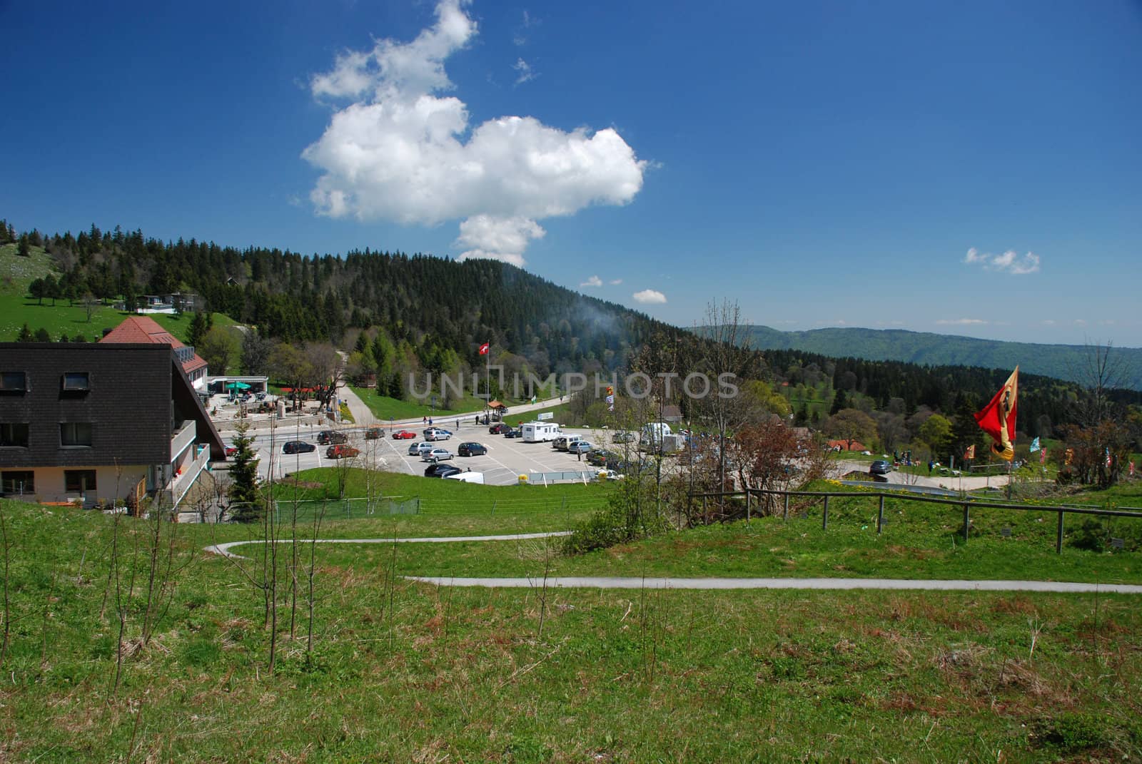 General picture of "Vue des Alpas" in Switzerland Jura with hotels, parking place, point of veu wrom were we can observe Alps, and wood and the sky at the background