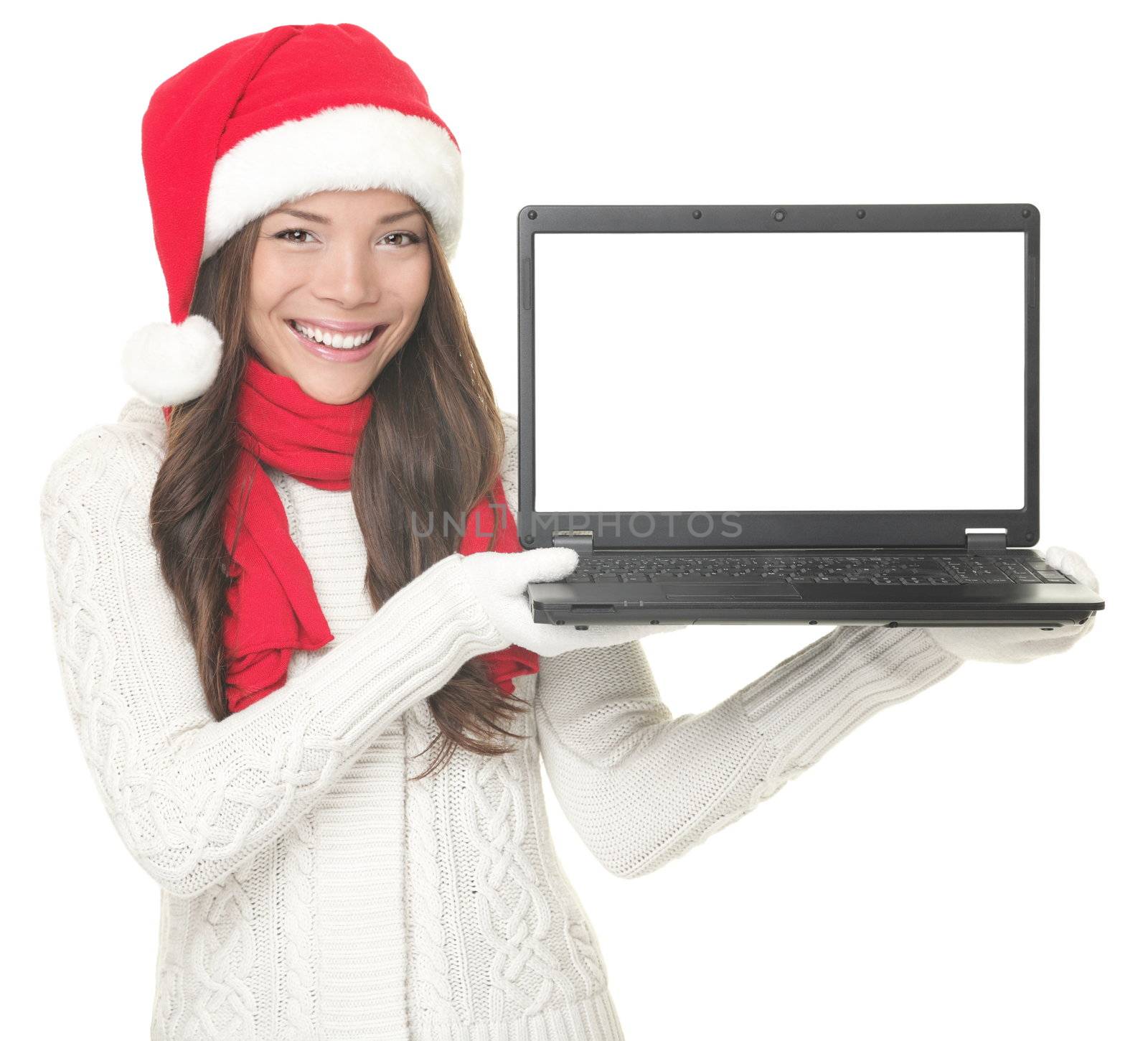  Laptop christmas girl. Smiling young woman in santa hat and sweater showing laptop. Copy space on computer screen. Caucasian Asian female model isolated on white background. 
