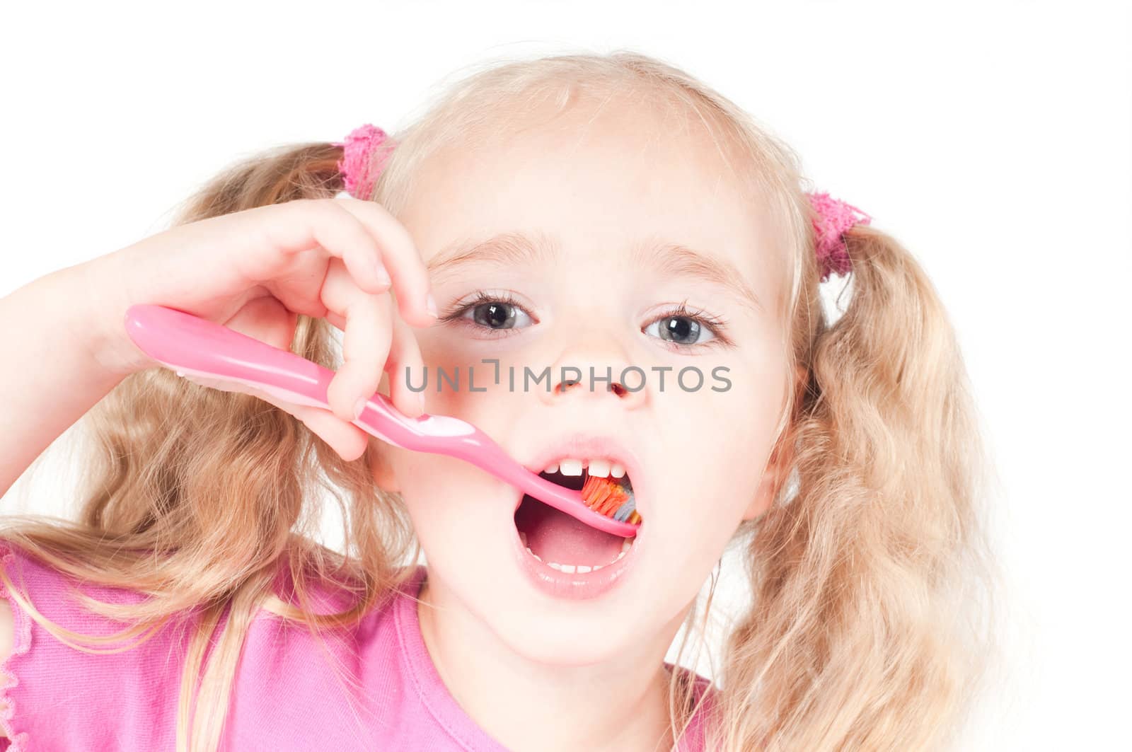 Little cute girl in pink and with ponytails in studio