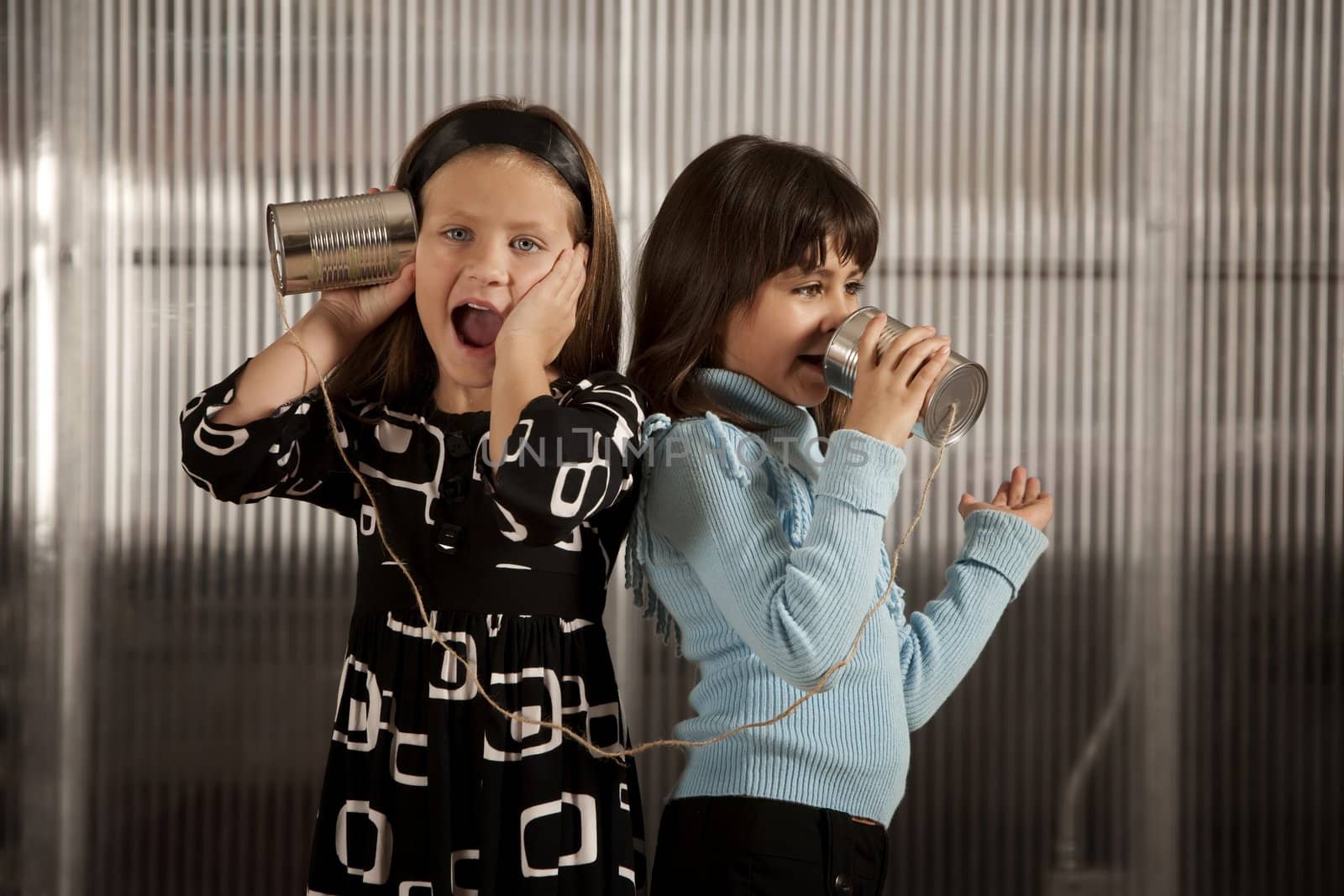 Little gril getting shocking message from friend on tin can phone