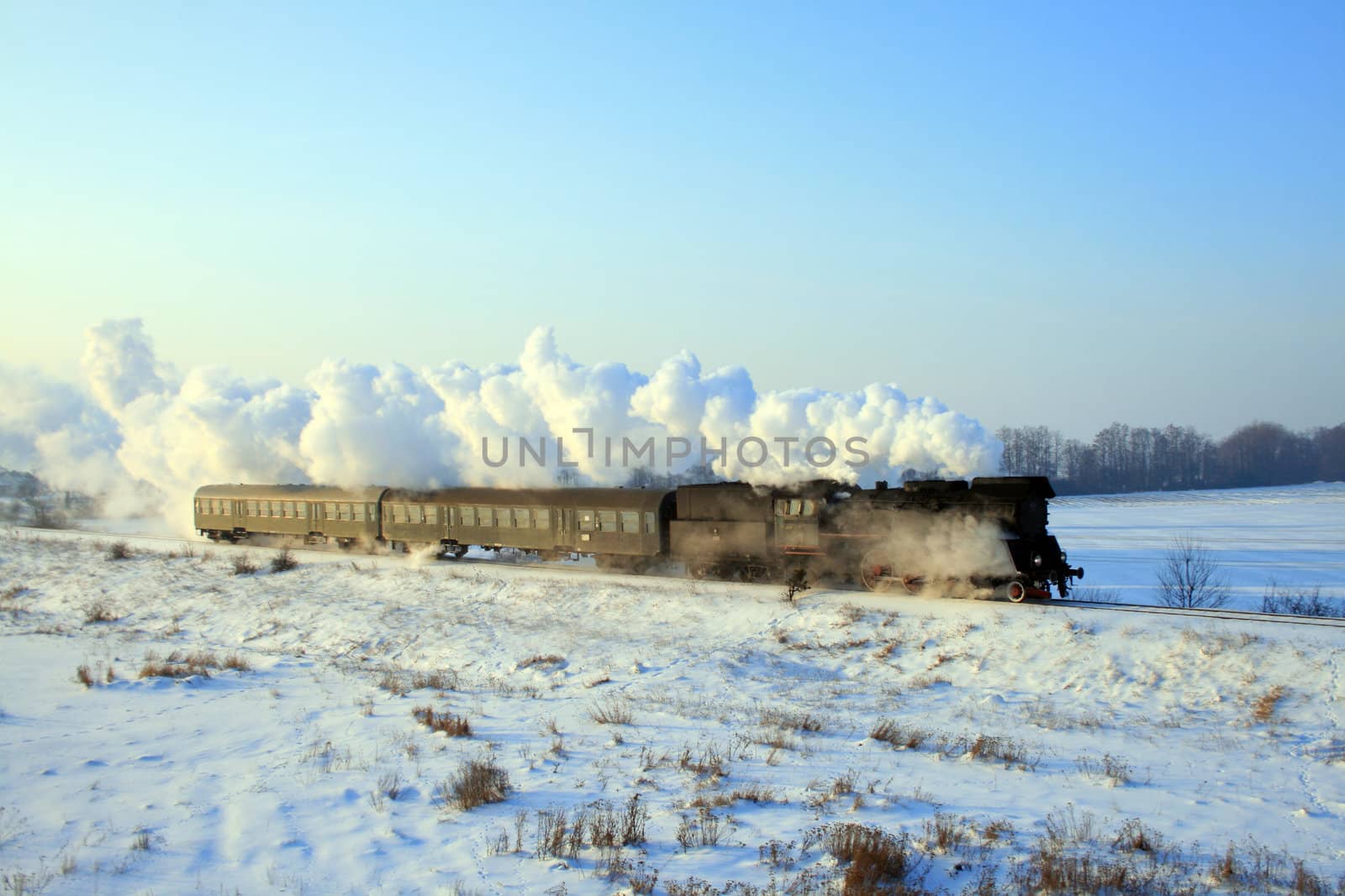 Vintage steam train passing through snowy countryside