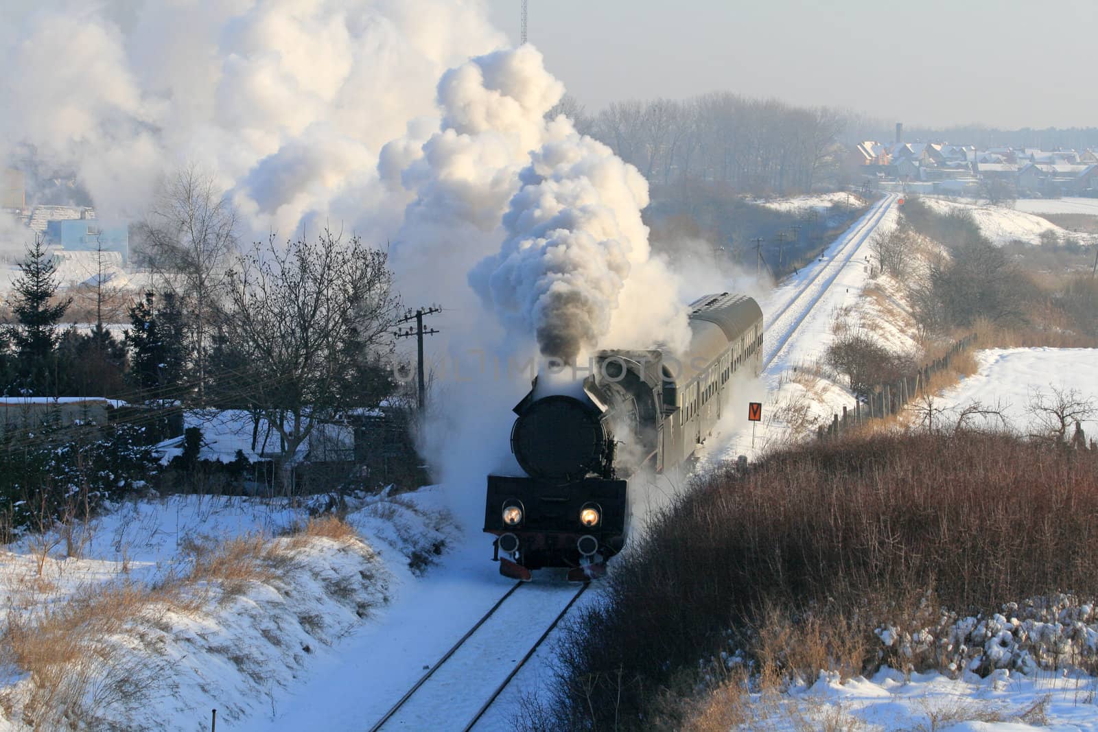 Vintage steam train passing through snowy countryside