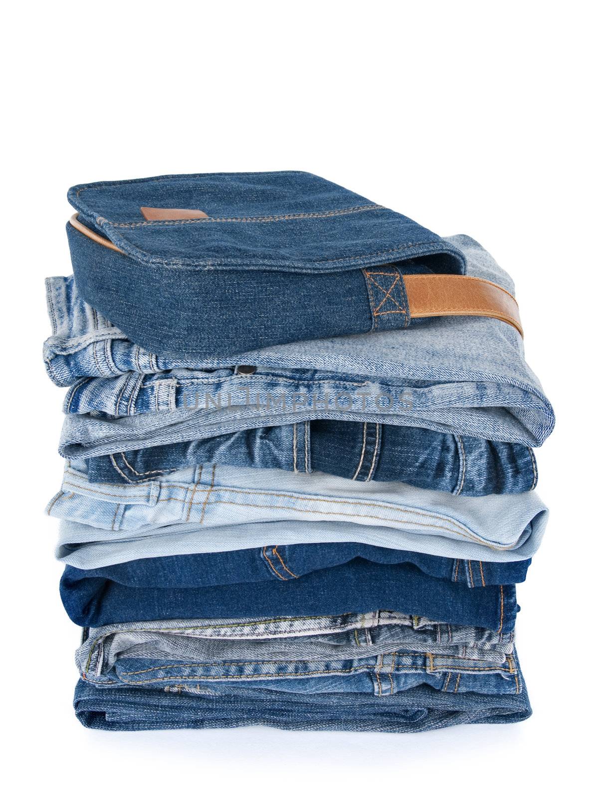 Stack of jeans and a denim bag on white background.