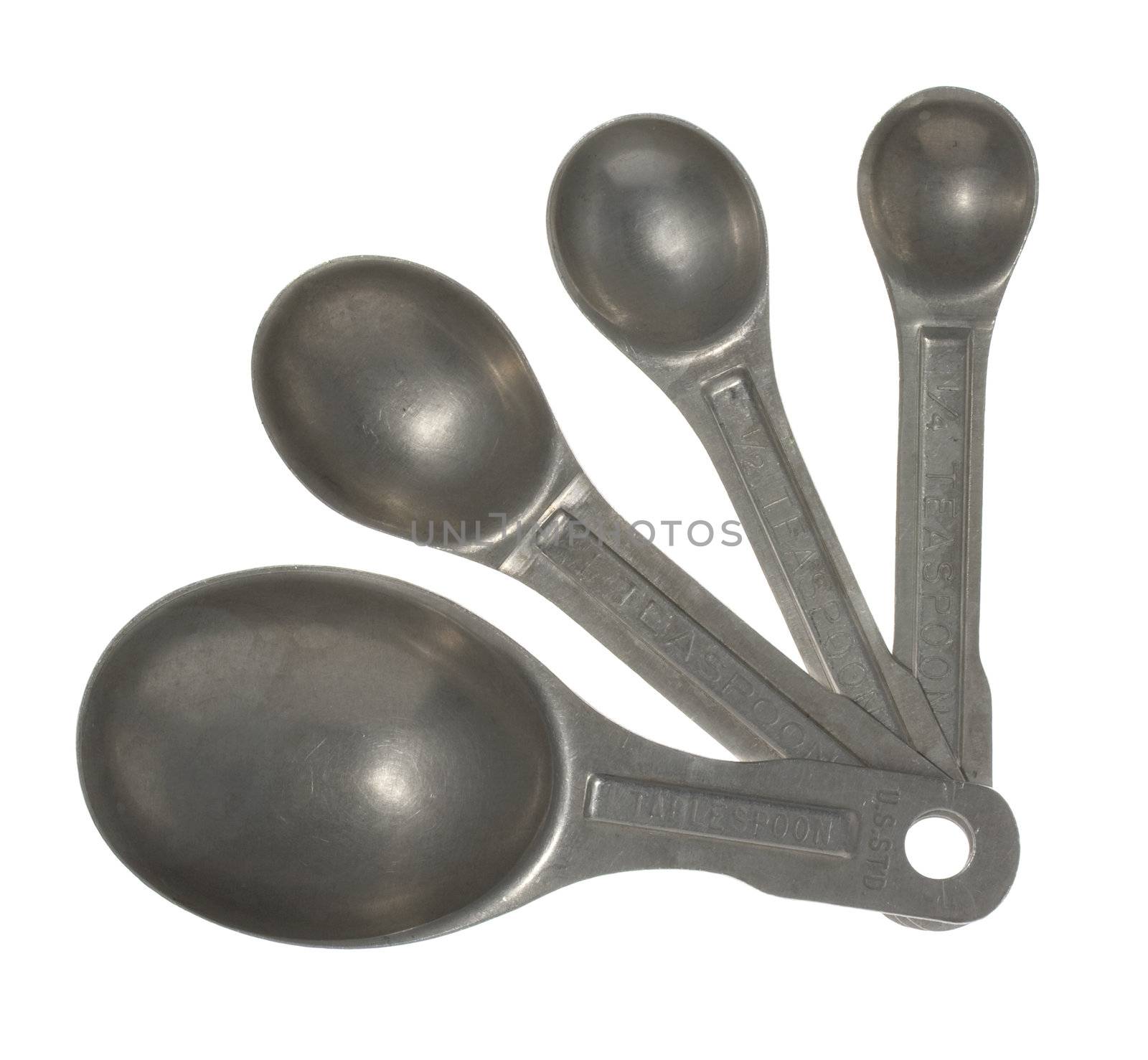 A set of four old, scratched aluminum measuring spoons isolated on white