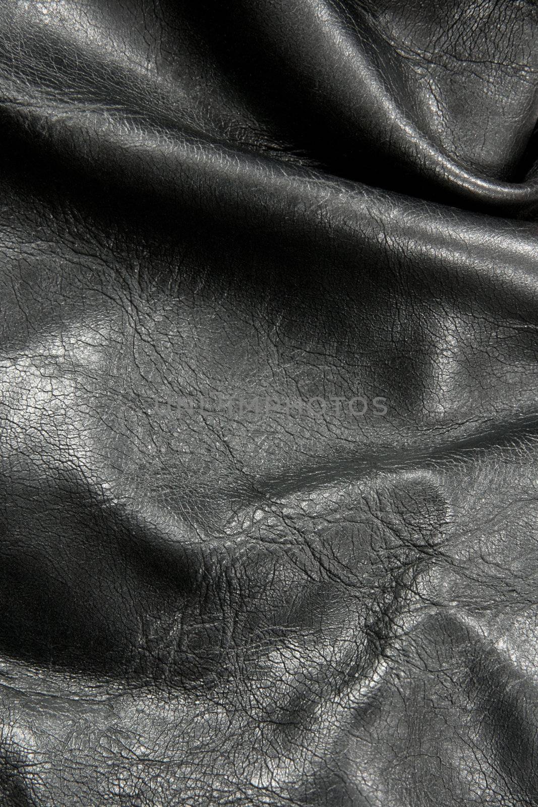 Closeup of crumpled shiny black leather texture.