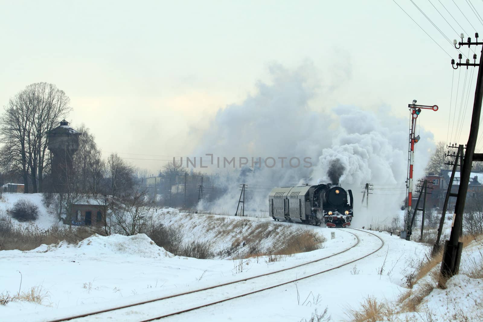 Vintage steam train passing through snowy countryside