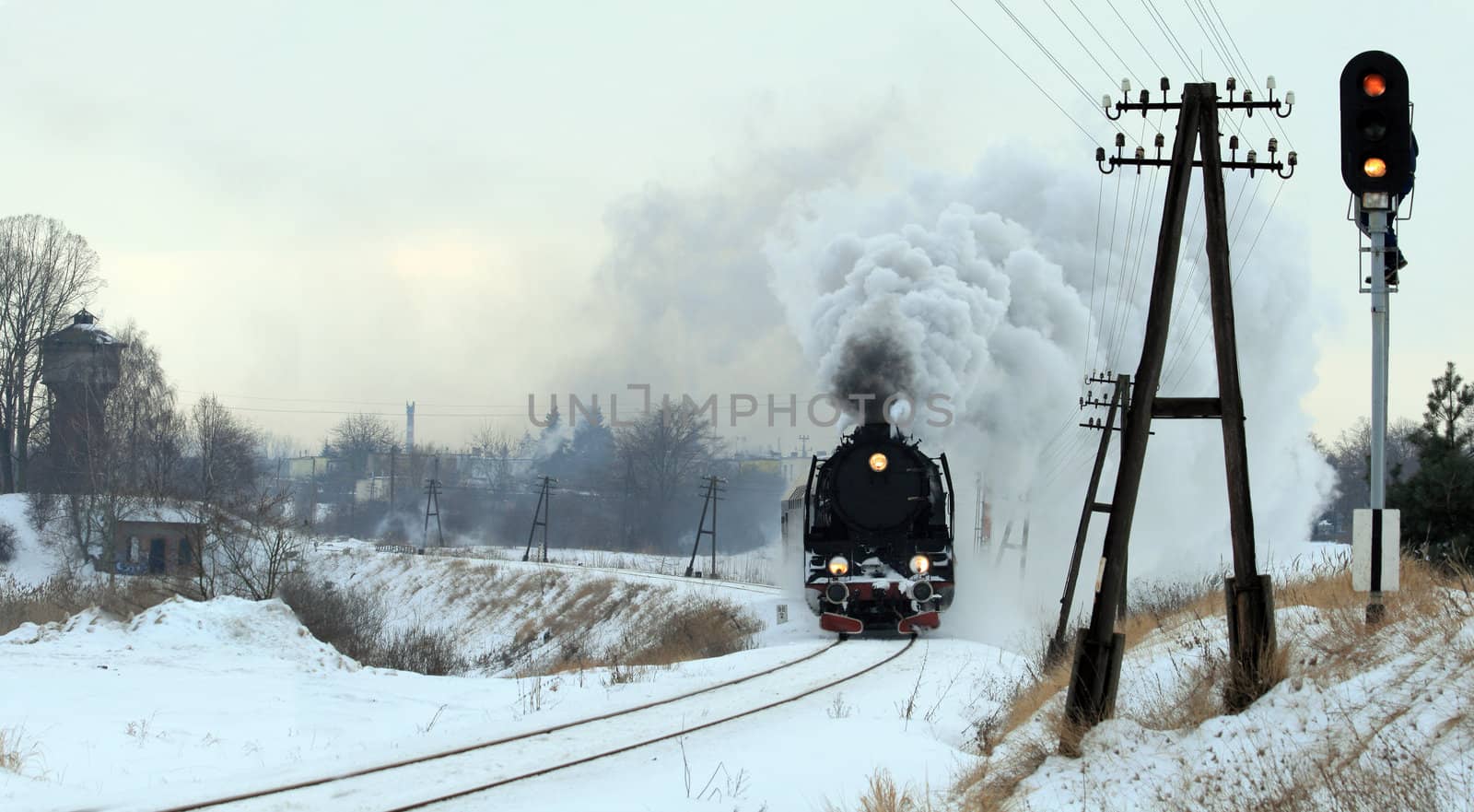 Vintage steam train passing through snowy countryside