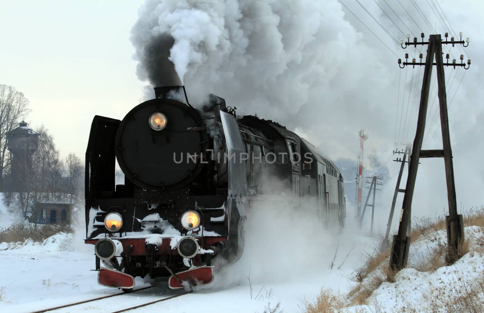 Vintage steam train passing through snowy countryside