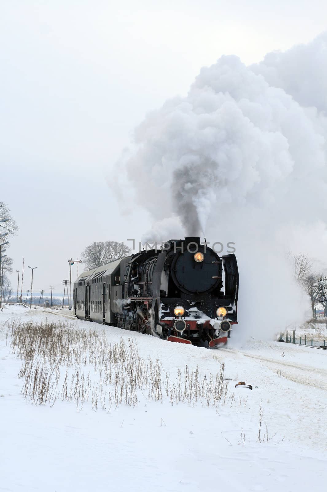 Old retro steam train starting from the station during wintertime