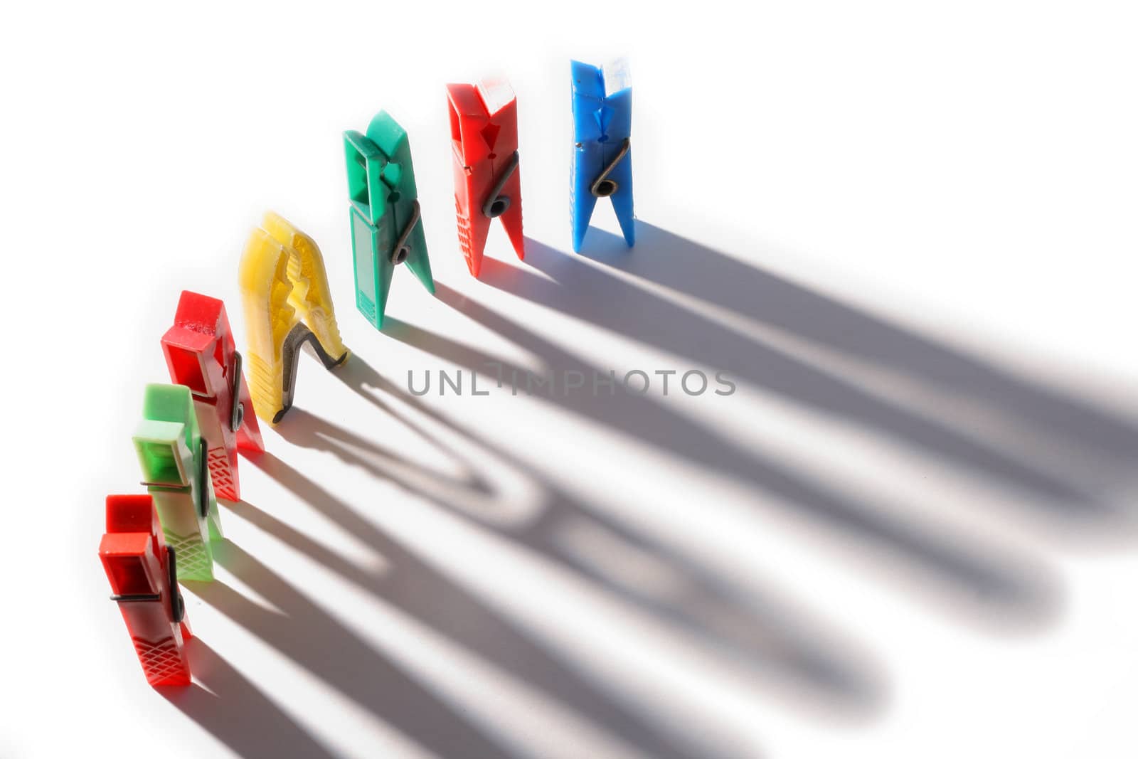 Colorful clothes pegs in a row with shadows
