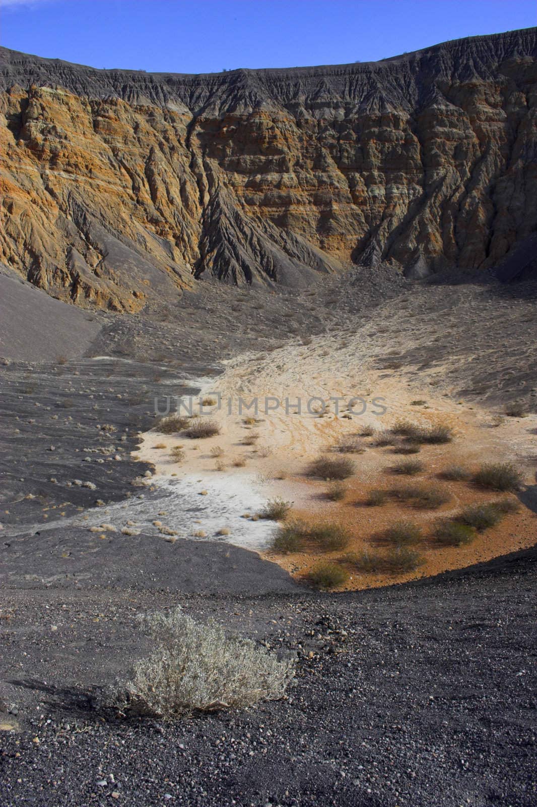 Fragment of black lava and ornage clay and salt mineral deposits in geological formations in Ubehebe Volcano, Death Valley National Park