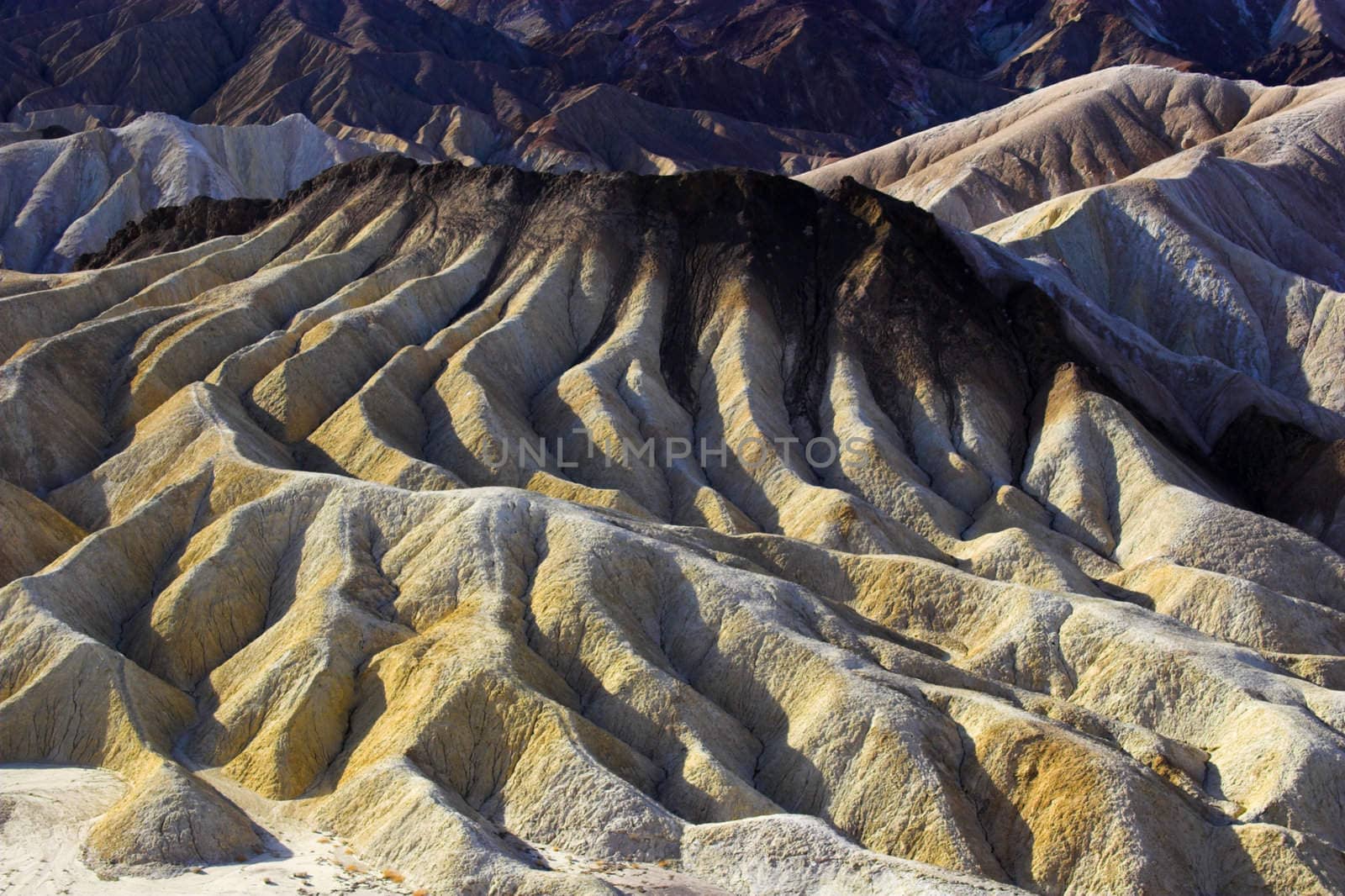 Desert landscape with multicolored yellow clay and salt mineral deposits in geological formations of Death Valley National Park