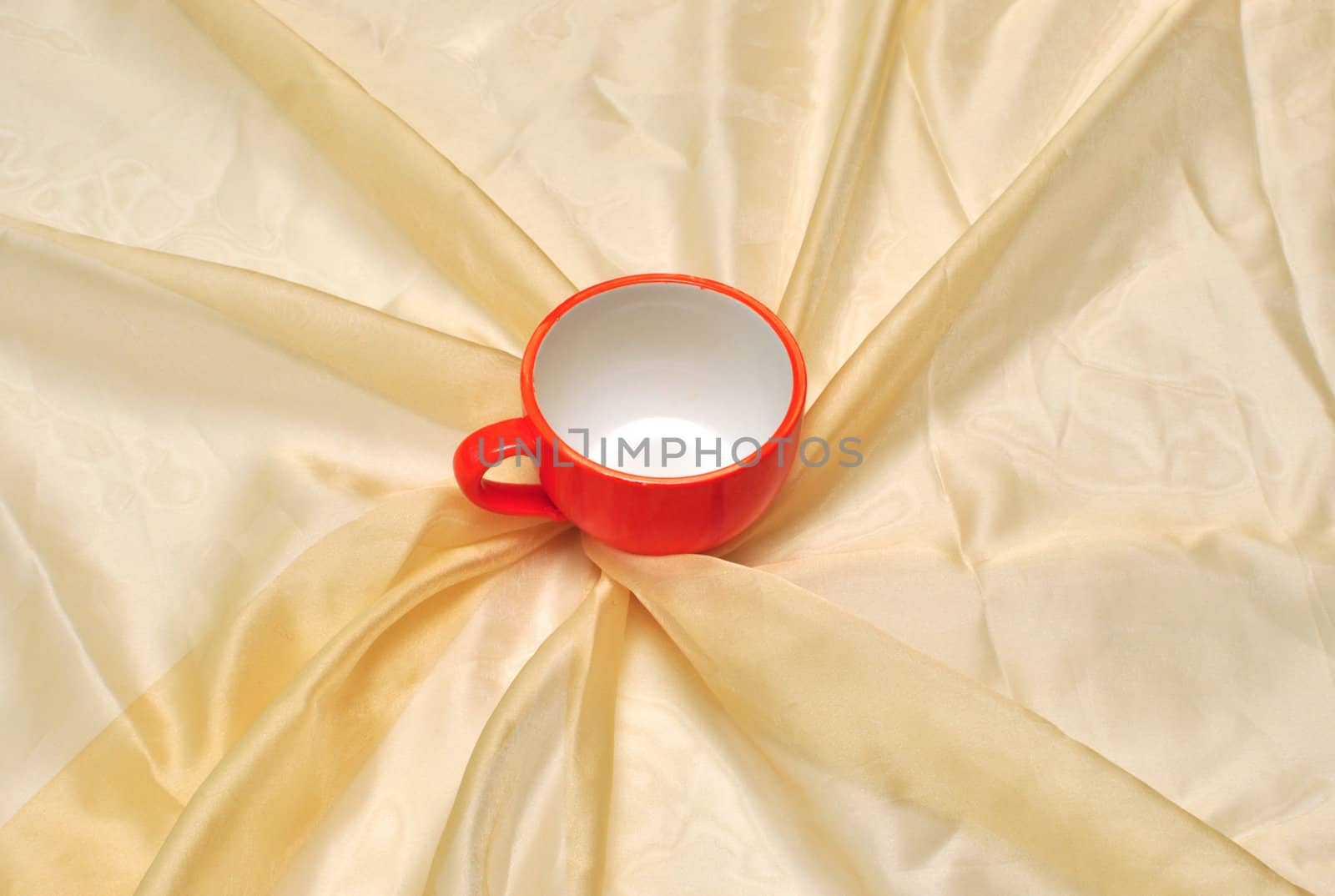 photo of single red cup at the golden fabric drapery 
