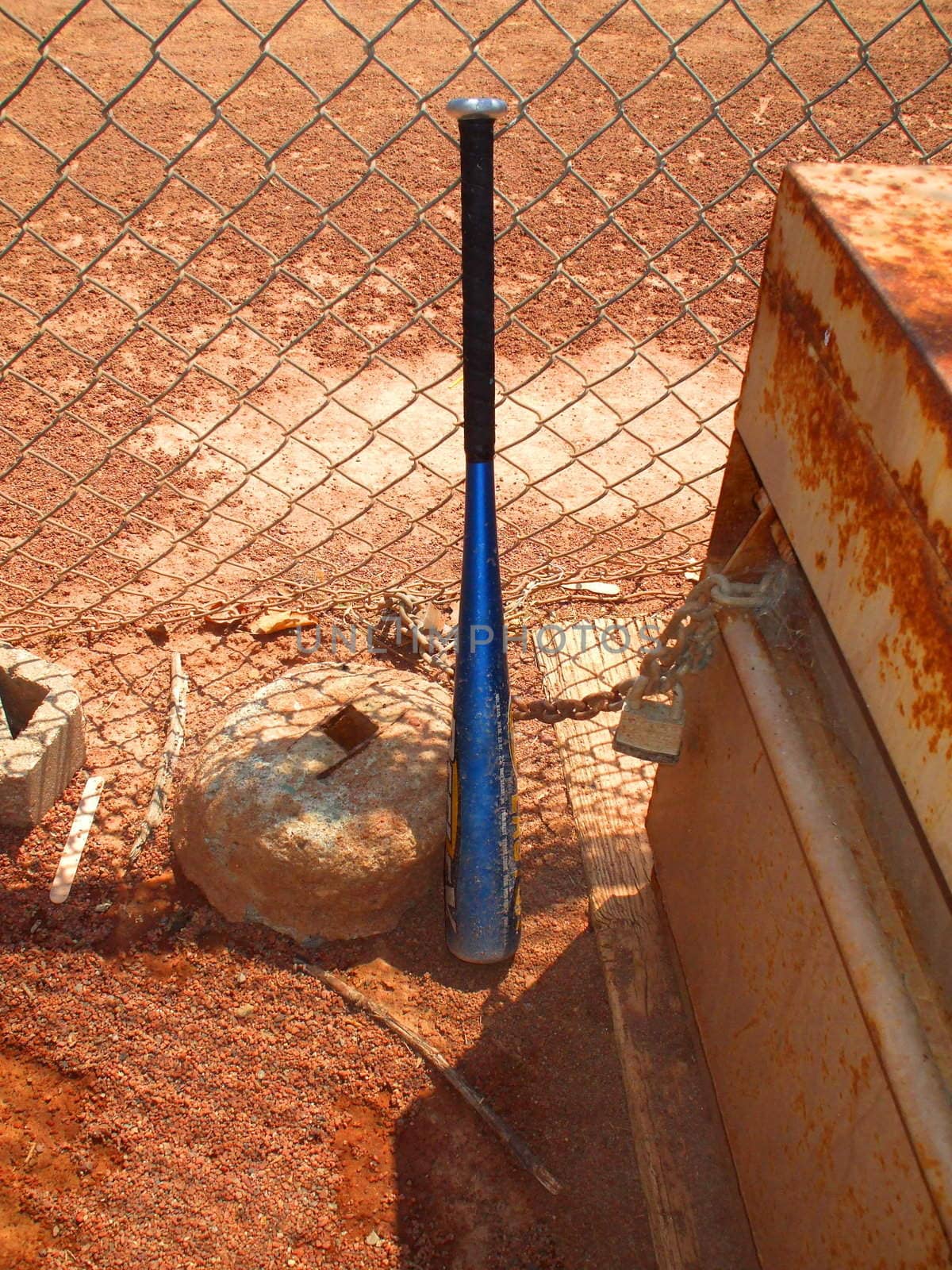 Baseball bat next to a fence.