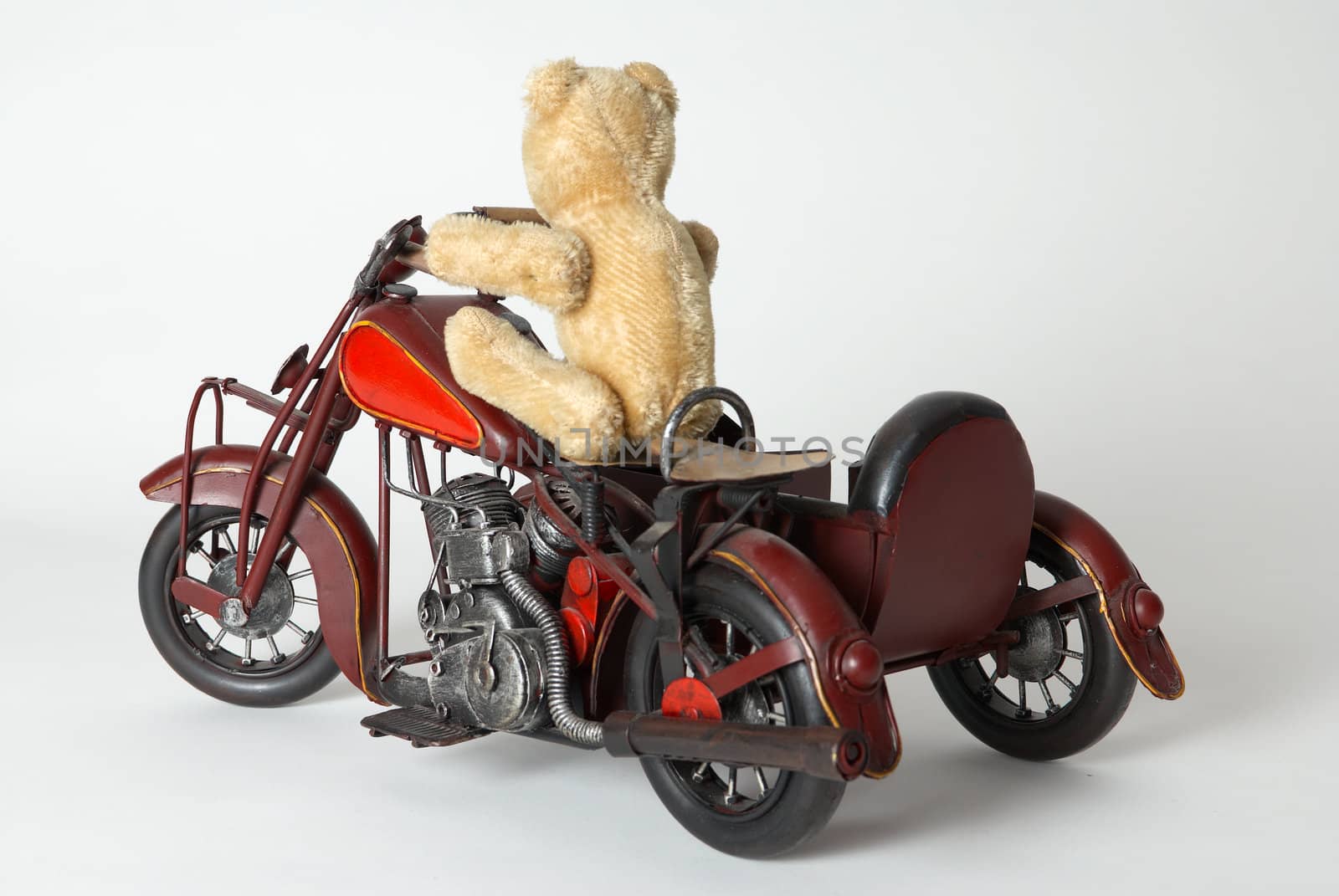 Teddy bear riding a toy motorbike