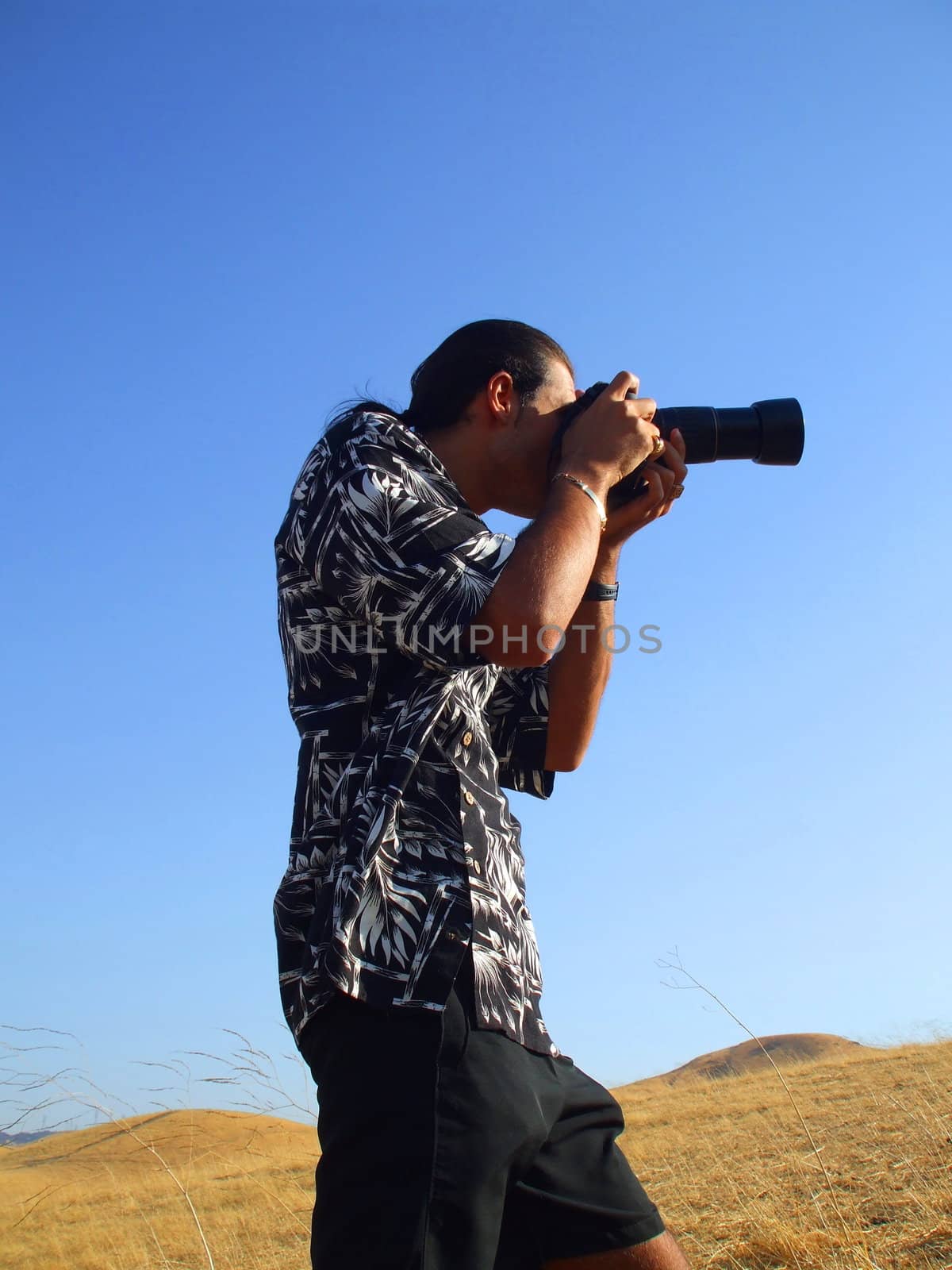 Young man photographer holding a photo camera outdoors.