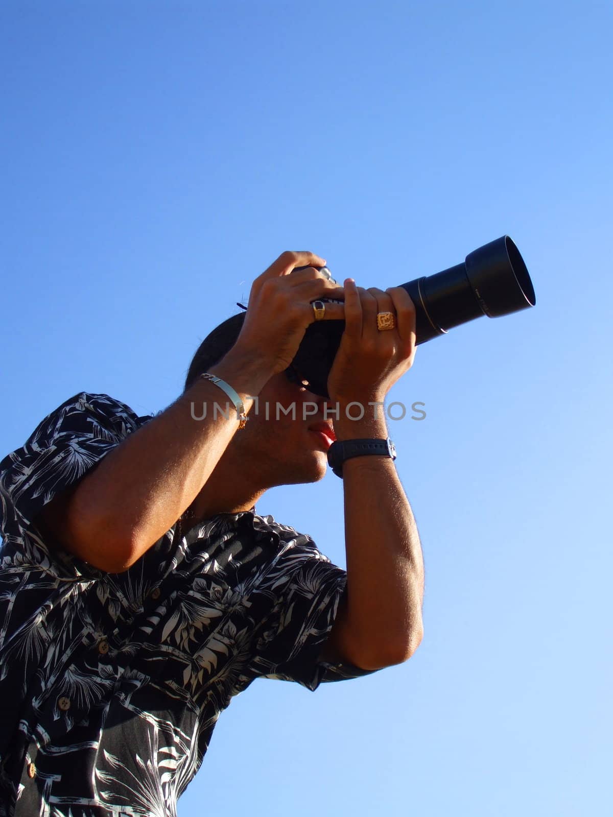 Young man photographer holding a photo camera outdoors.