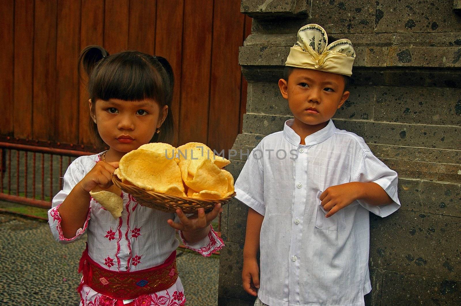 Indonesian children, wearing traditional Balinese clothes carrying Krupuk Udang (Prawn/Shrimp crackers), Jimbaran, Bali, Indonesia.