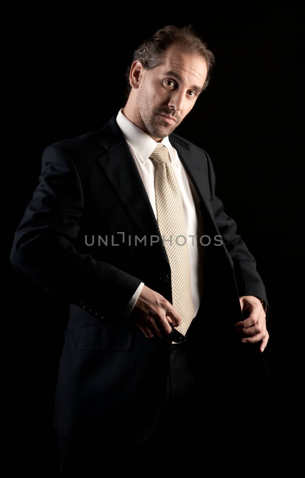 businessman buttoning jacket, getting dressed, on dark background by dgmata