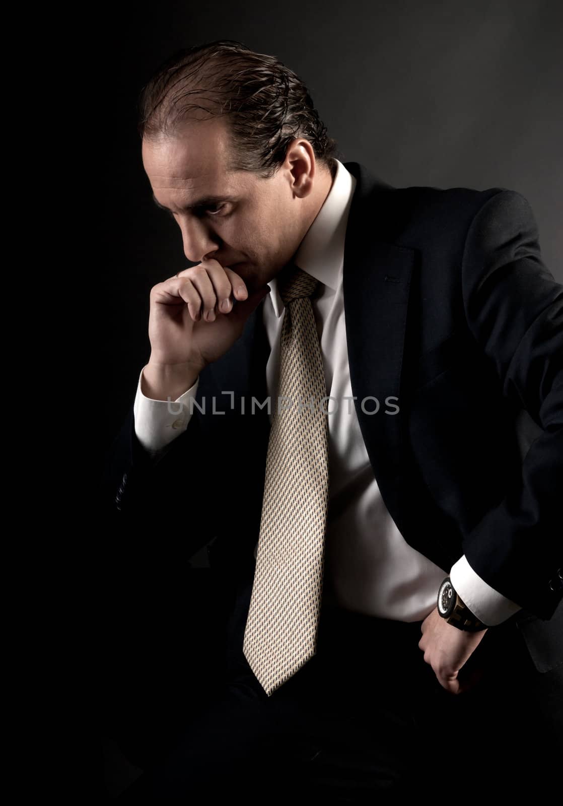 adult businessman serious thinking sitting on dark background