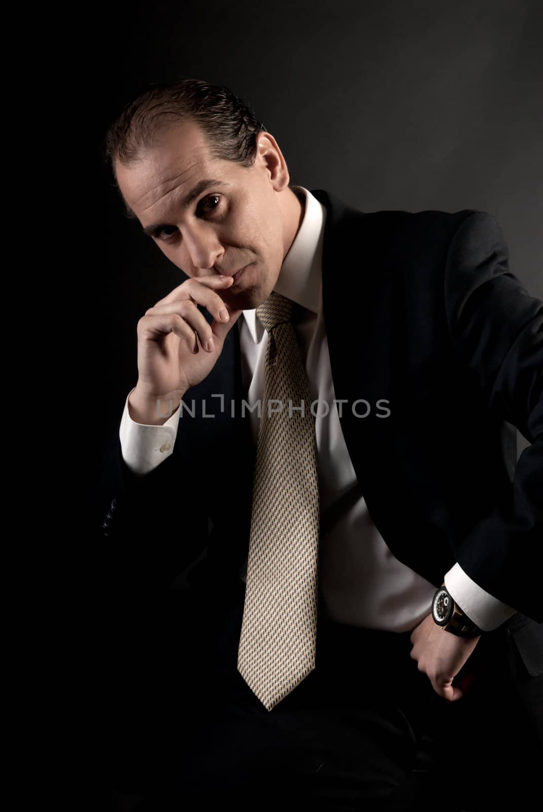 adult businessman serious thinking sitting on dark background