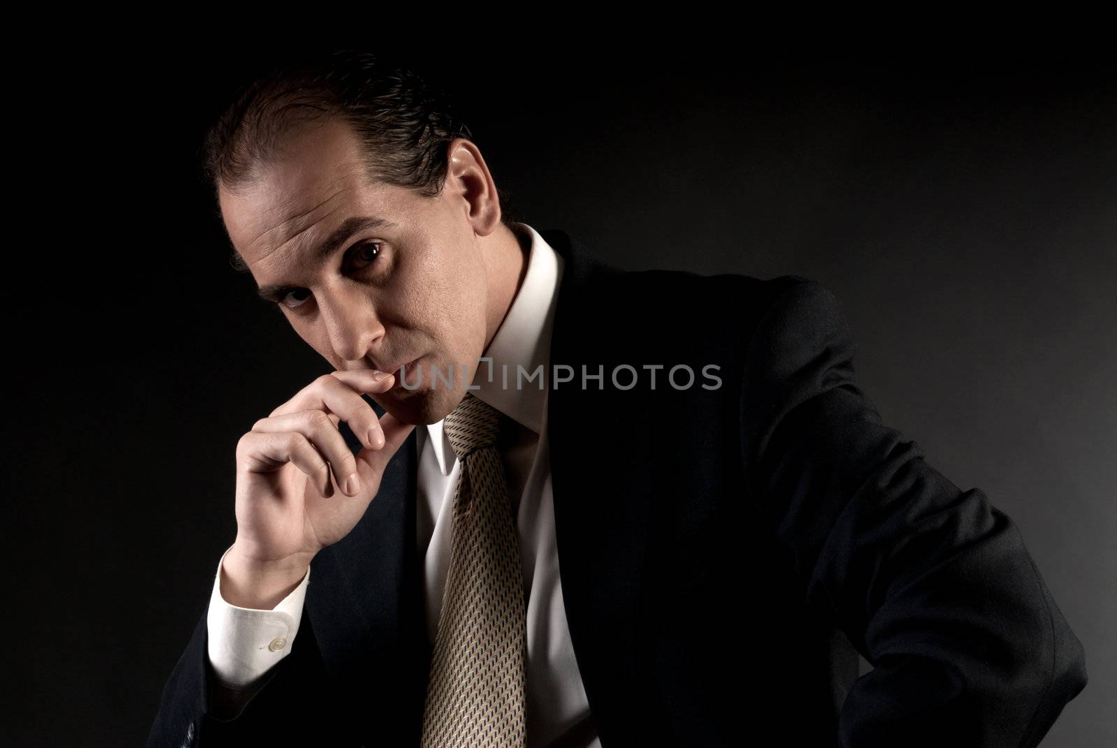 adult businessman serious thinking sitting on dark background by dgmata