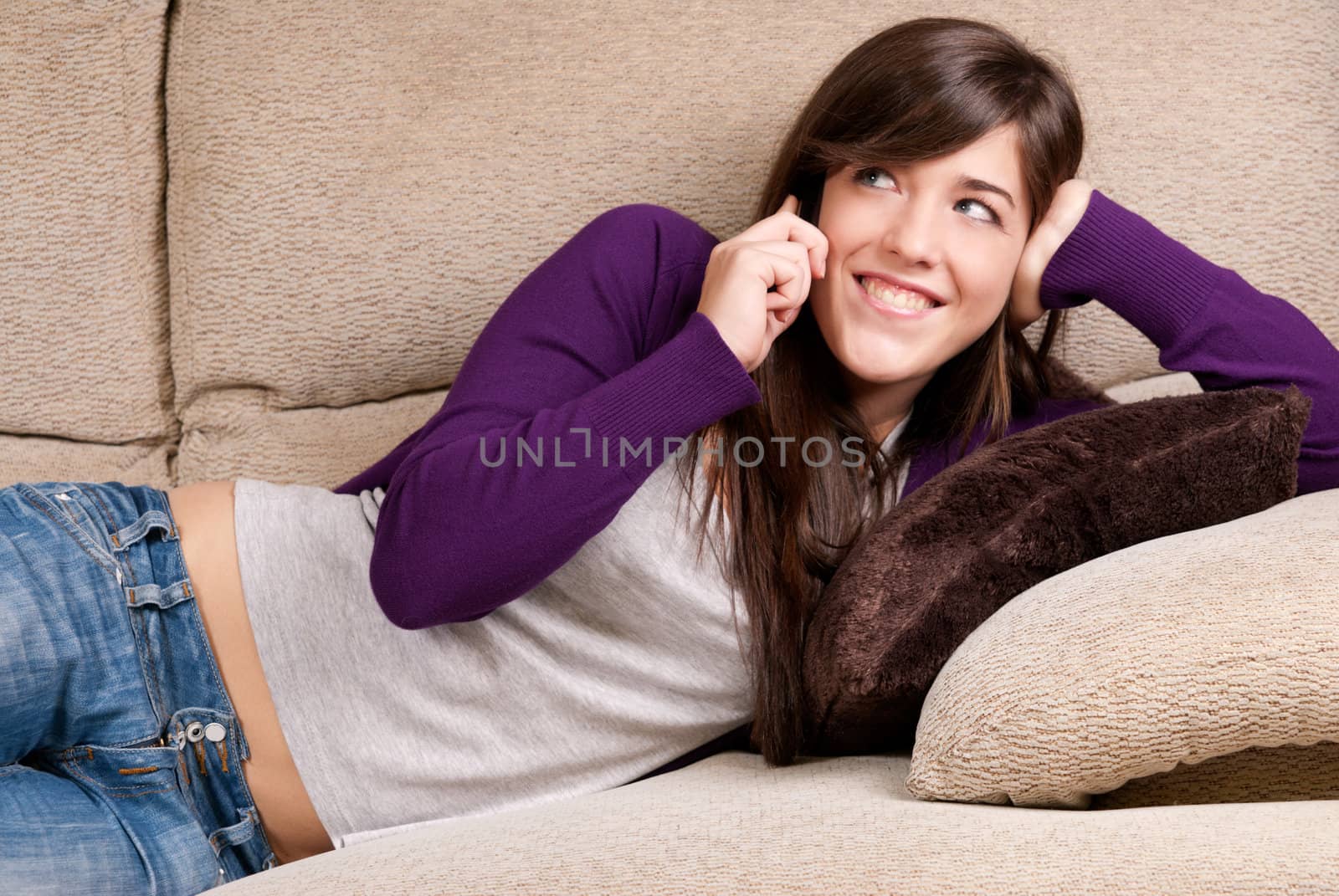 Young female talking by telephone laughing lying on couch