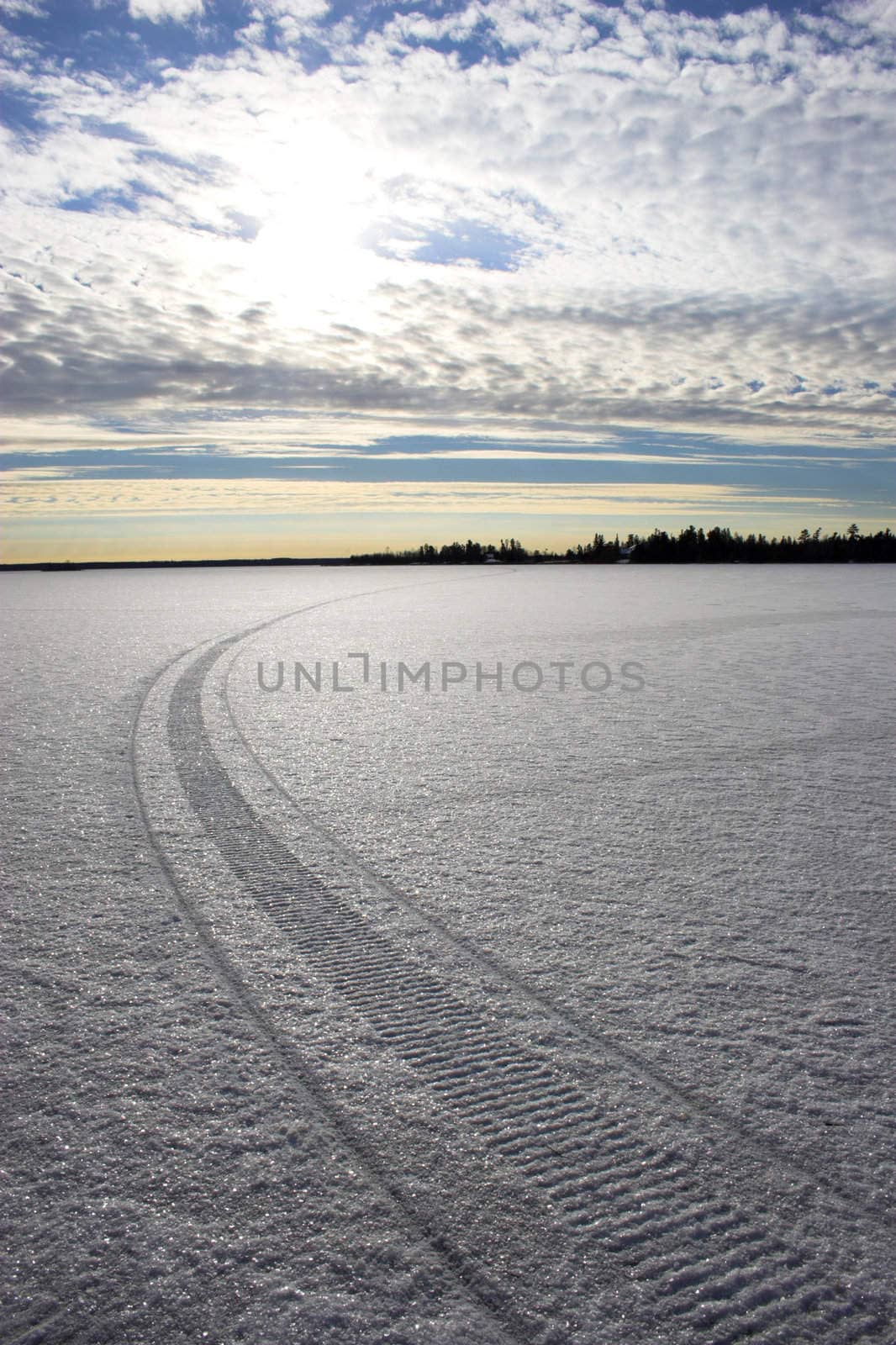 Snowmobile route over frozen lake with colorful reflections of the sun in snow crystals