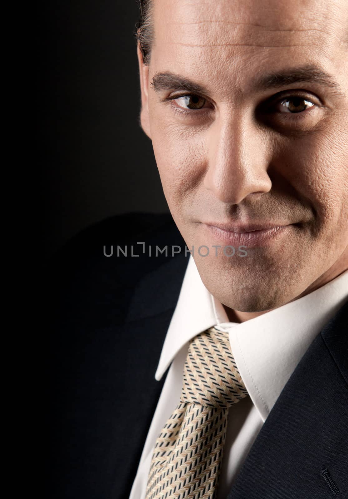 Adult businessman close-up portrait smiling on dark background. by dgmata