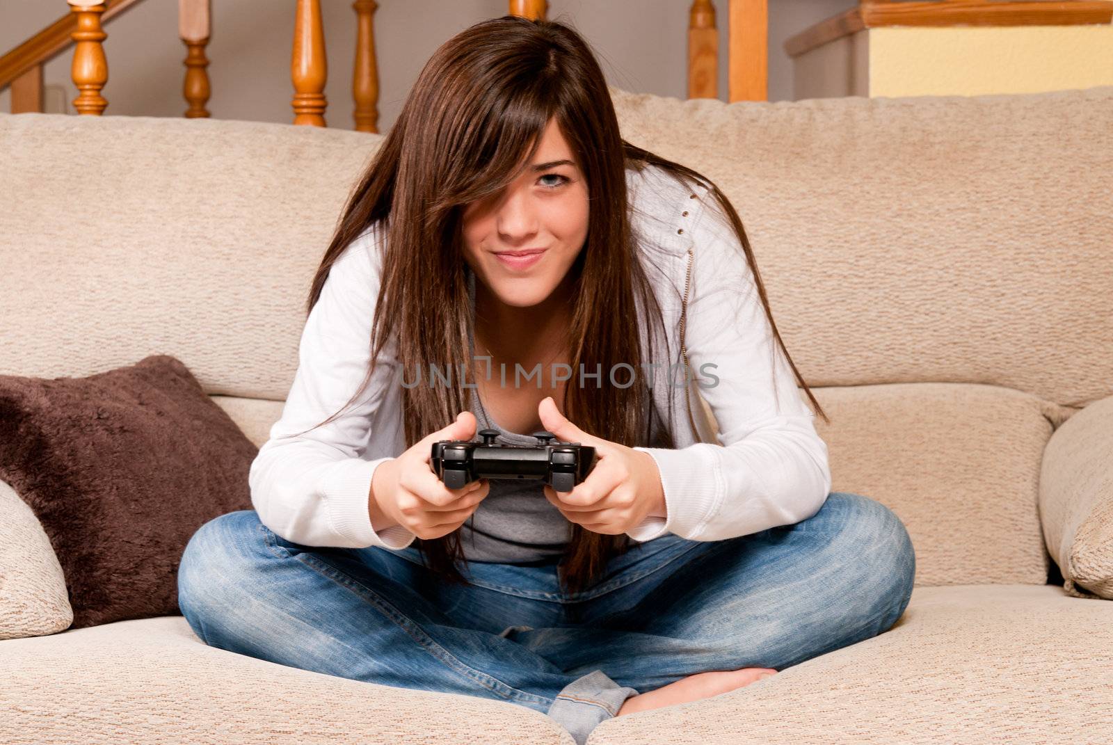 Young female concentrating playing videogames on sofa at home