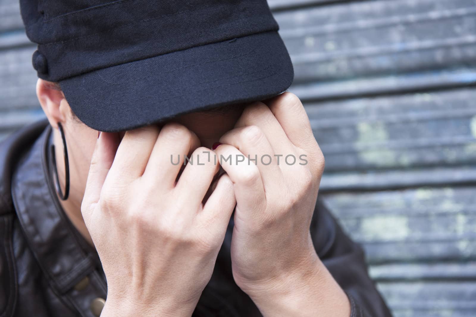 sulky young woman, wearing a cap, his face hidden in her hands