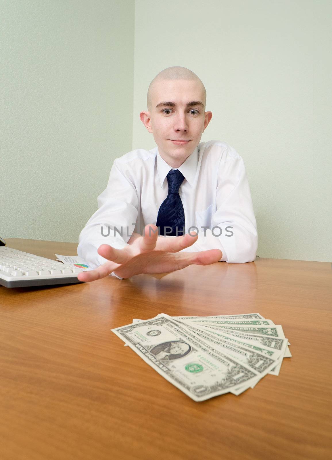 Young man reaches for a batch of money lying on a table