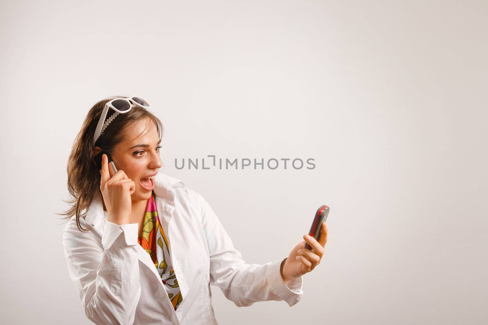 Modern looking young woman wearing white jacket talking on the phone