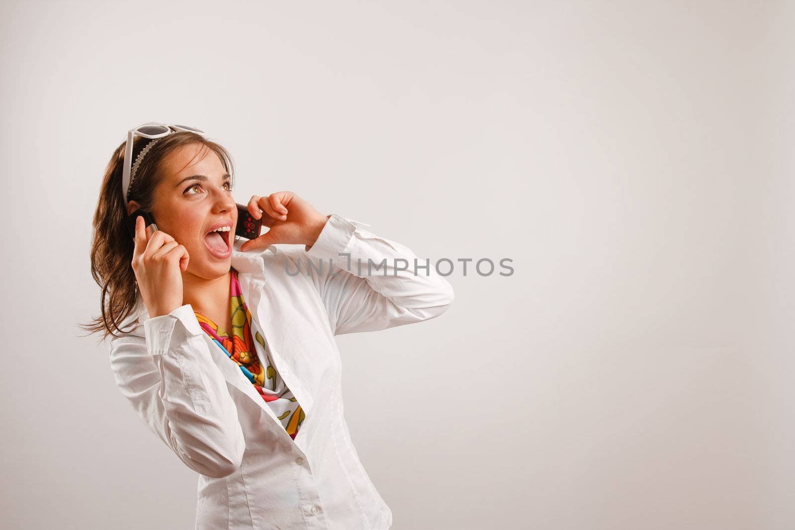 Modern looking young woman wearing white jacket talking on the phone
