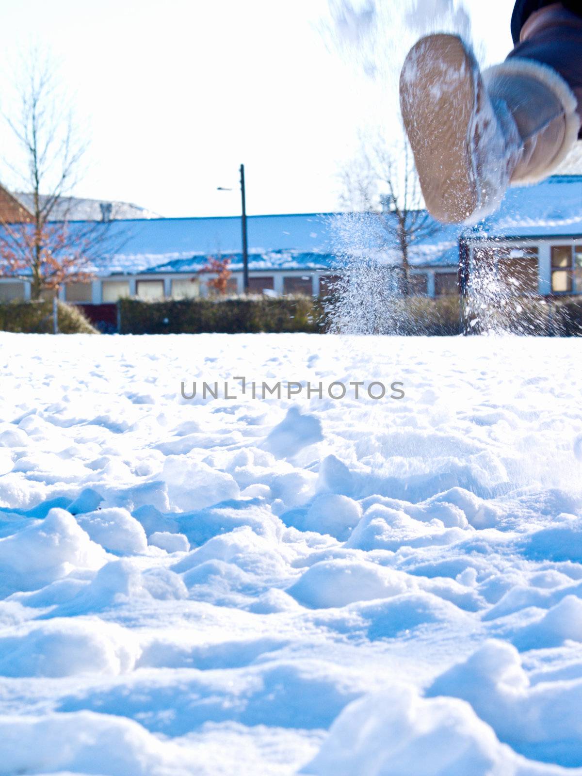 Boot kicking up snow in a field