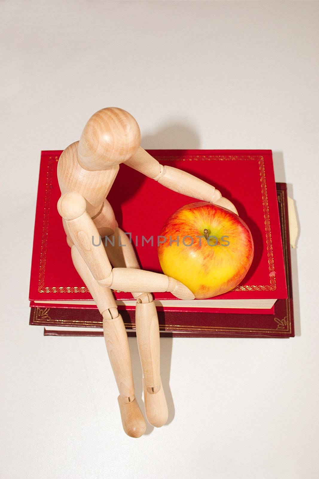 top view of a mannequin with a apple and sitting on books