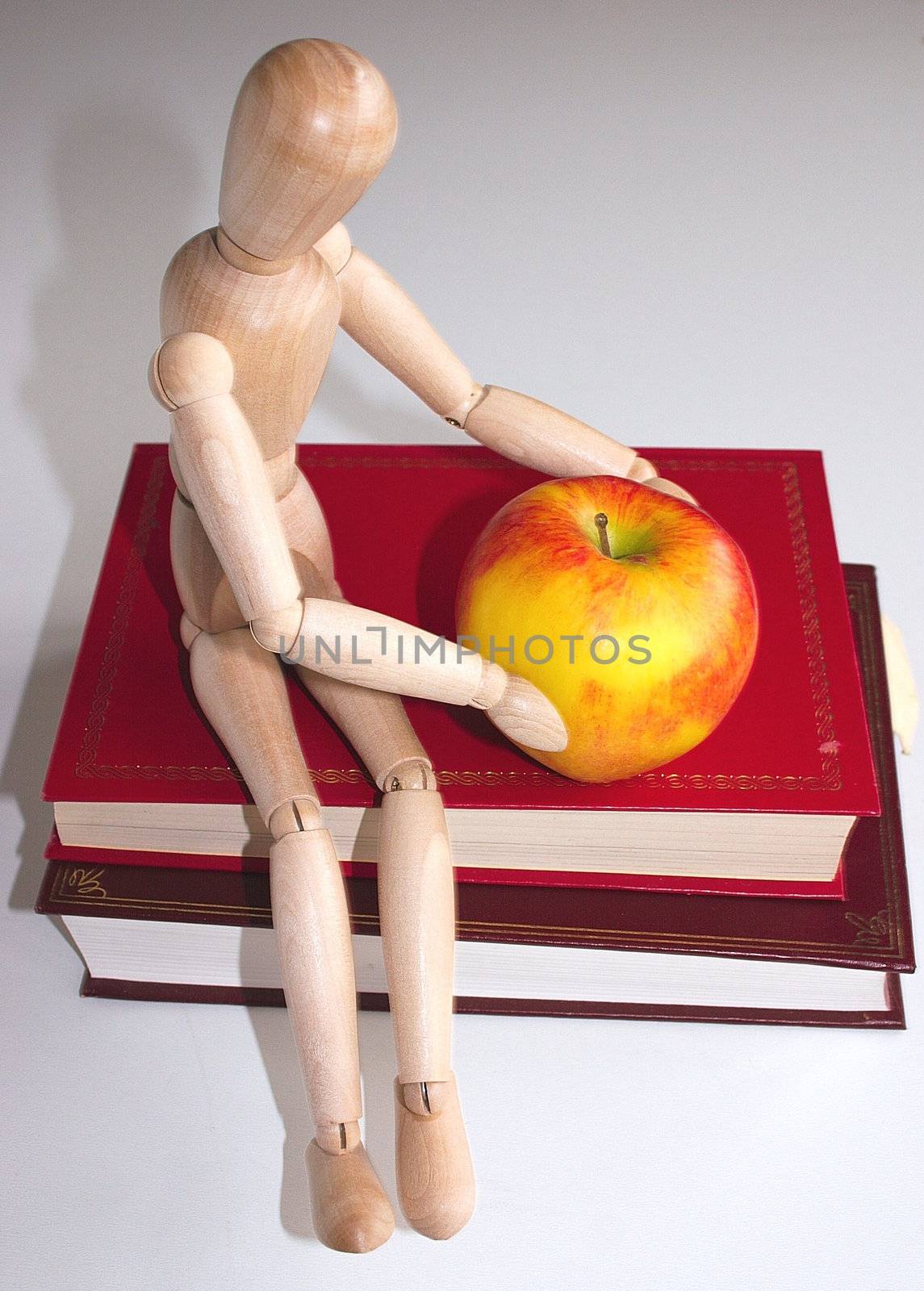 mannequin sitting on books with a apple for the teacher