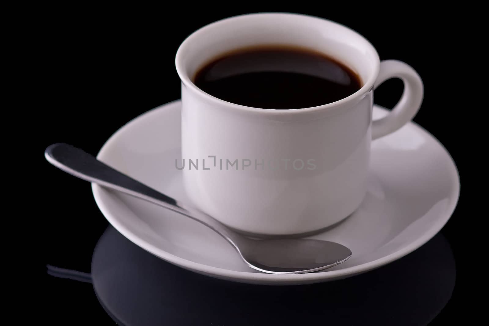 Black coffee in a white coffee cup. On a black mirroring surface.
