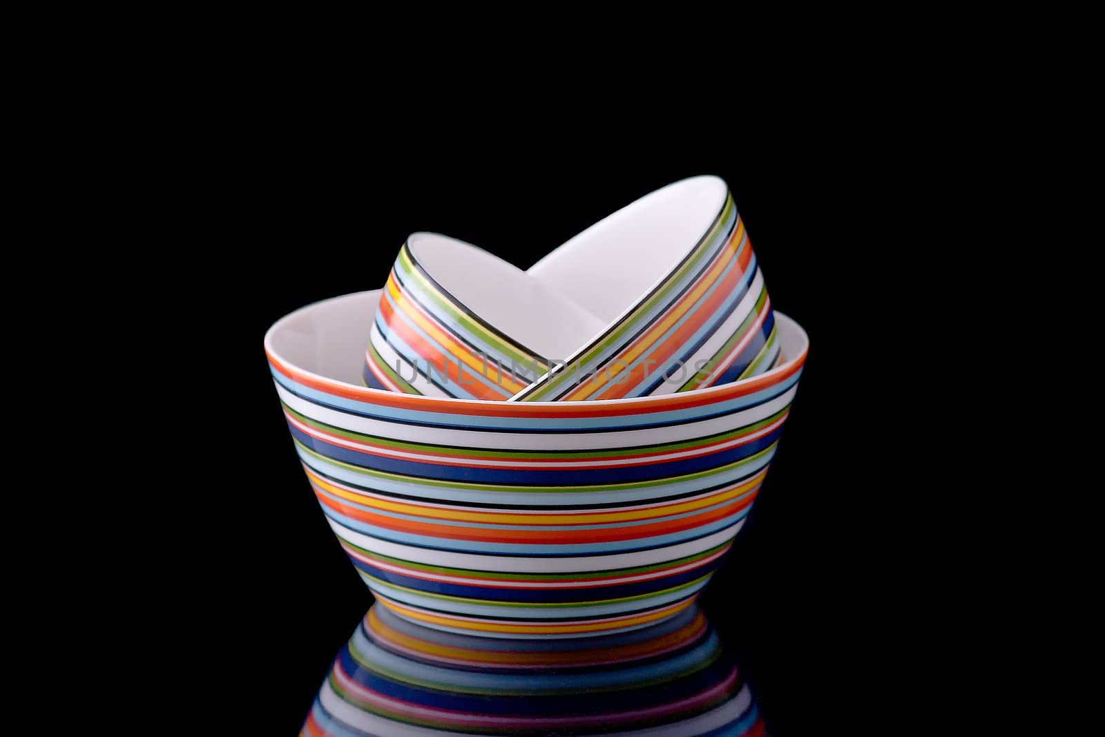 A stack of colorful bowls on a black mirror surface