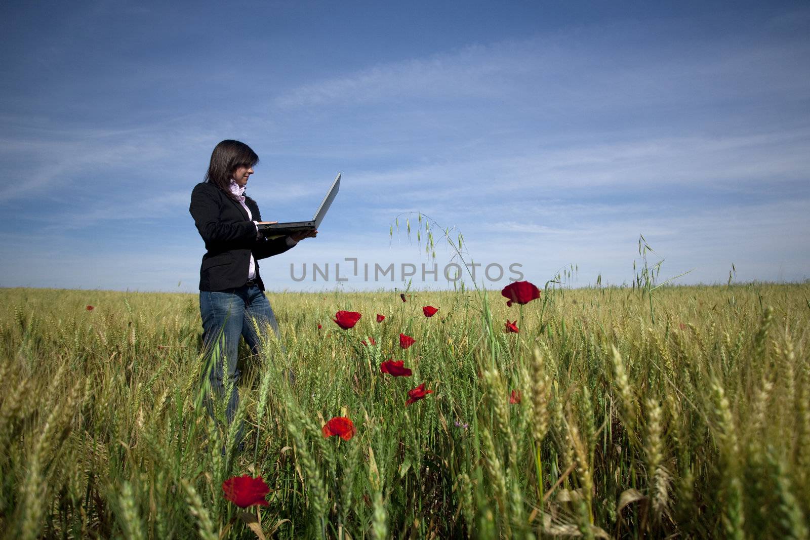 young businesswoman with laptop on poppie field by mlopes