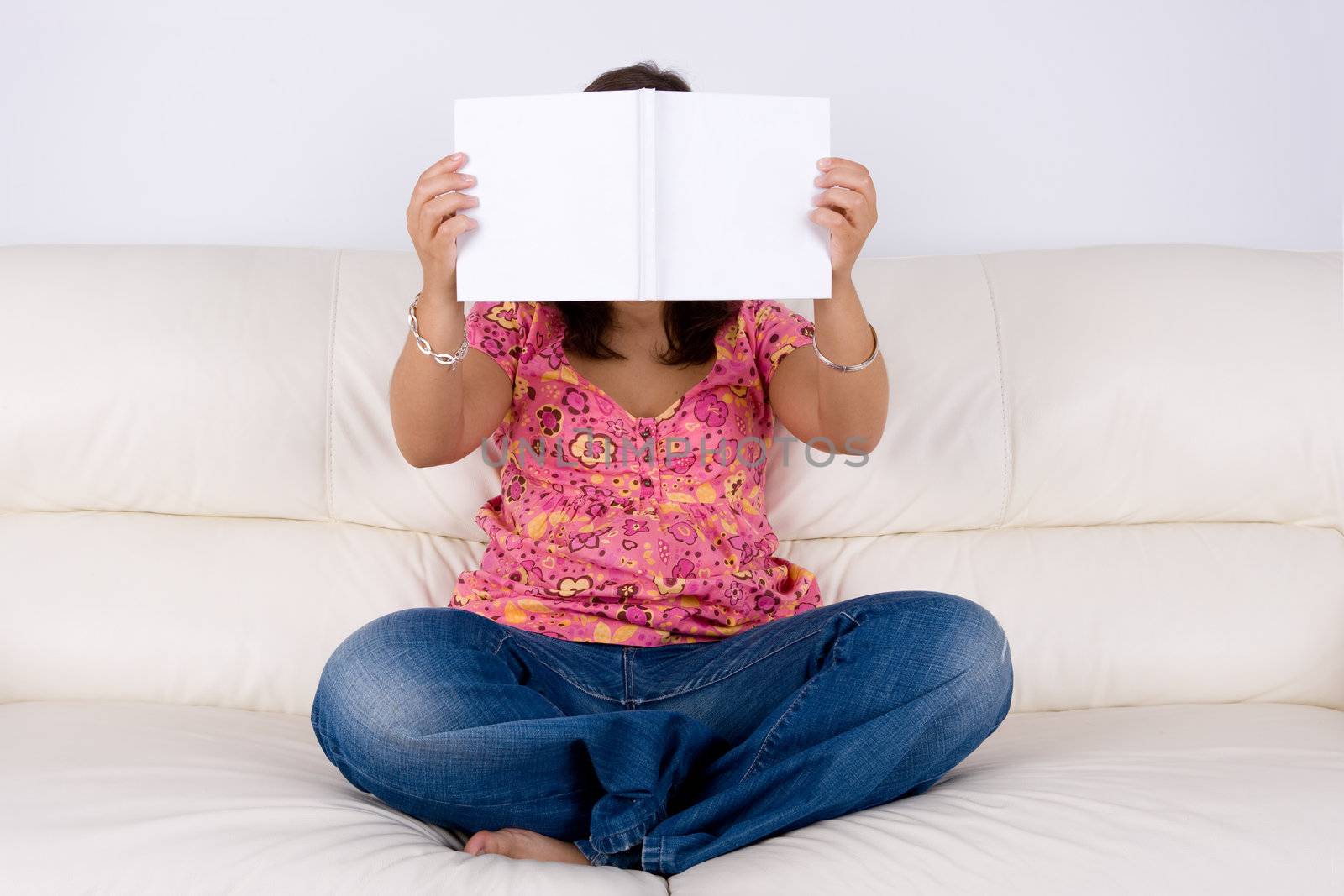 young woman sitting in the sofa reading white book