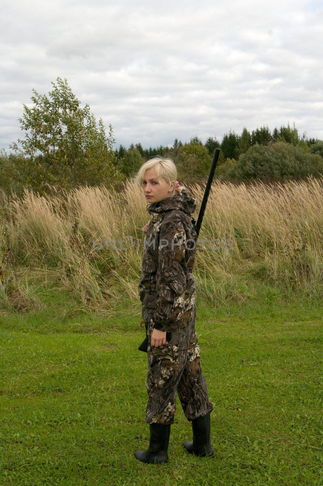 Blond girl in camouflage with a shotgun.