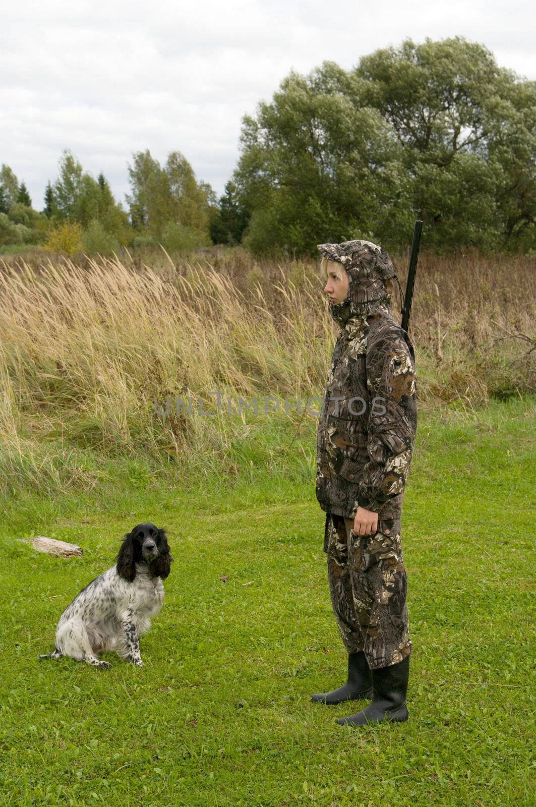 Blonde in camouflage with a gun and russian hunting spaniel.